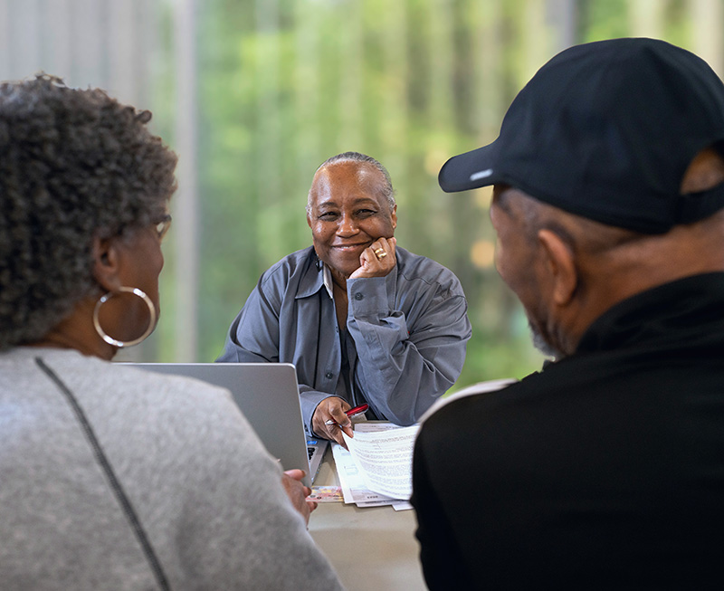 A Tax-Aide volunteer smiles at a couple she is helping with their tax return.